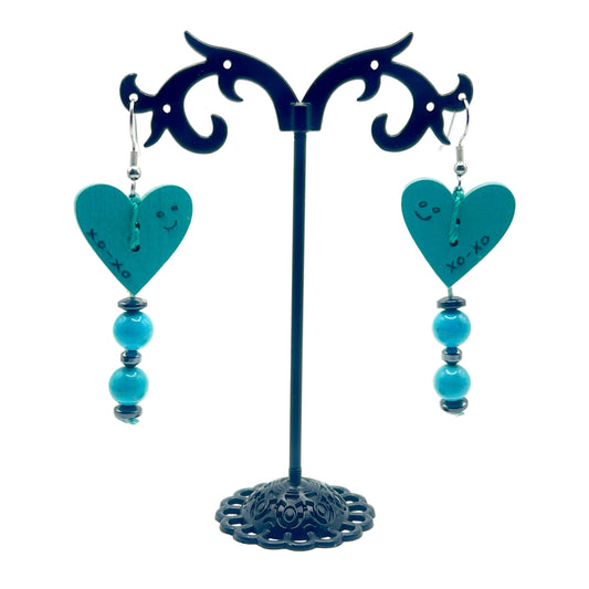 Unique Pair of turquoise heart-shaped earrings on a decorative stand against a white background