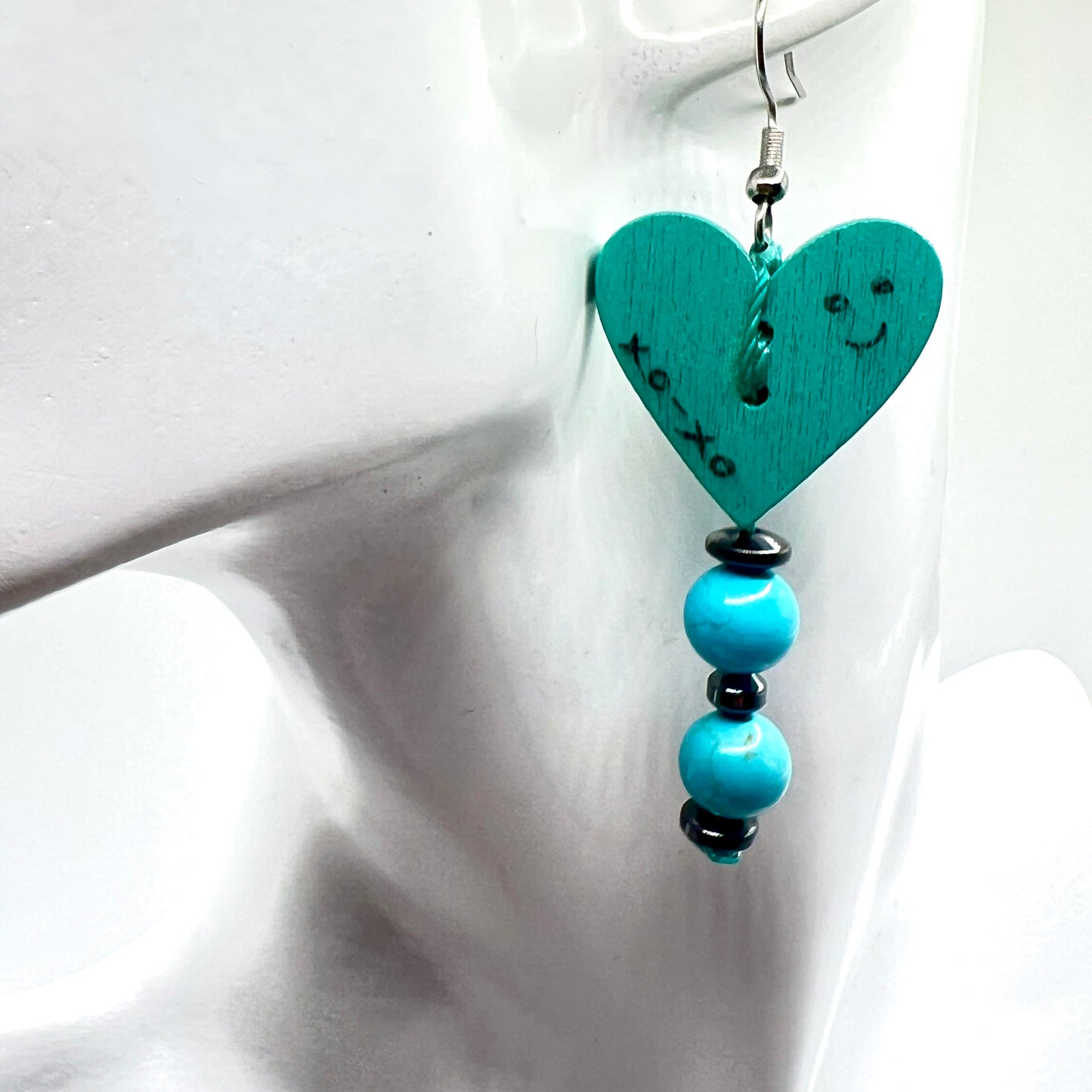 Handmade Teal heart-shaped earring with beads on a white background